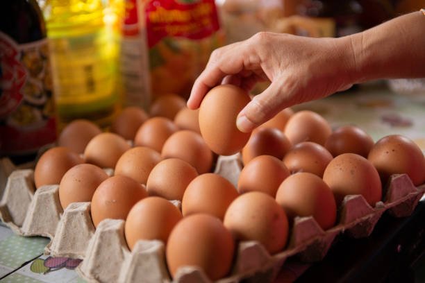 The cook takes the eggs from the tray for cooking.